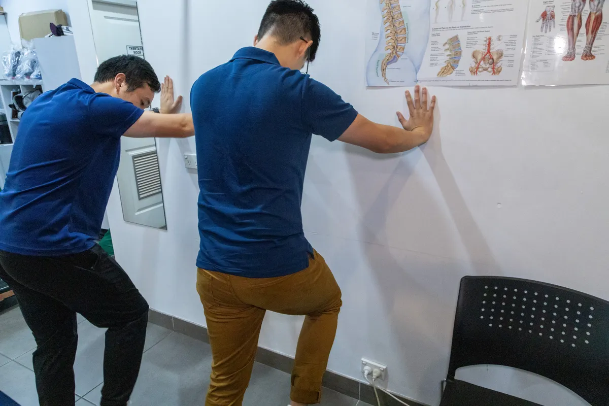 Physiotherapist guiding a patient through a standing hip exercise